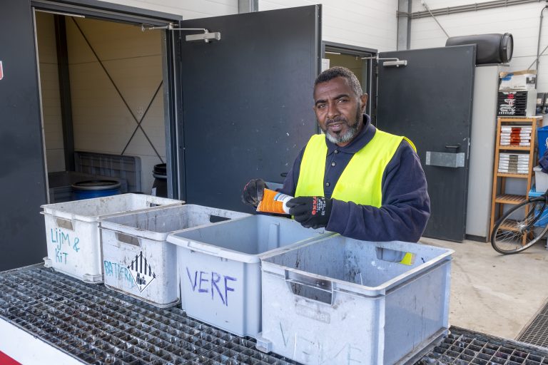 Afbeelding van medewerker van de millieustraat die afval aan het scheiden is.