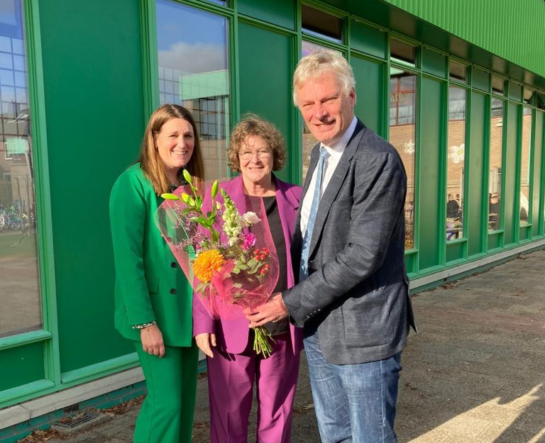 Wethouder Wubbo Tempel overhandigt een bos bloemen aan het schoolbestuur.