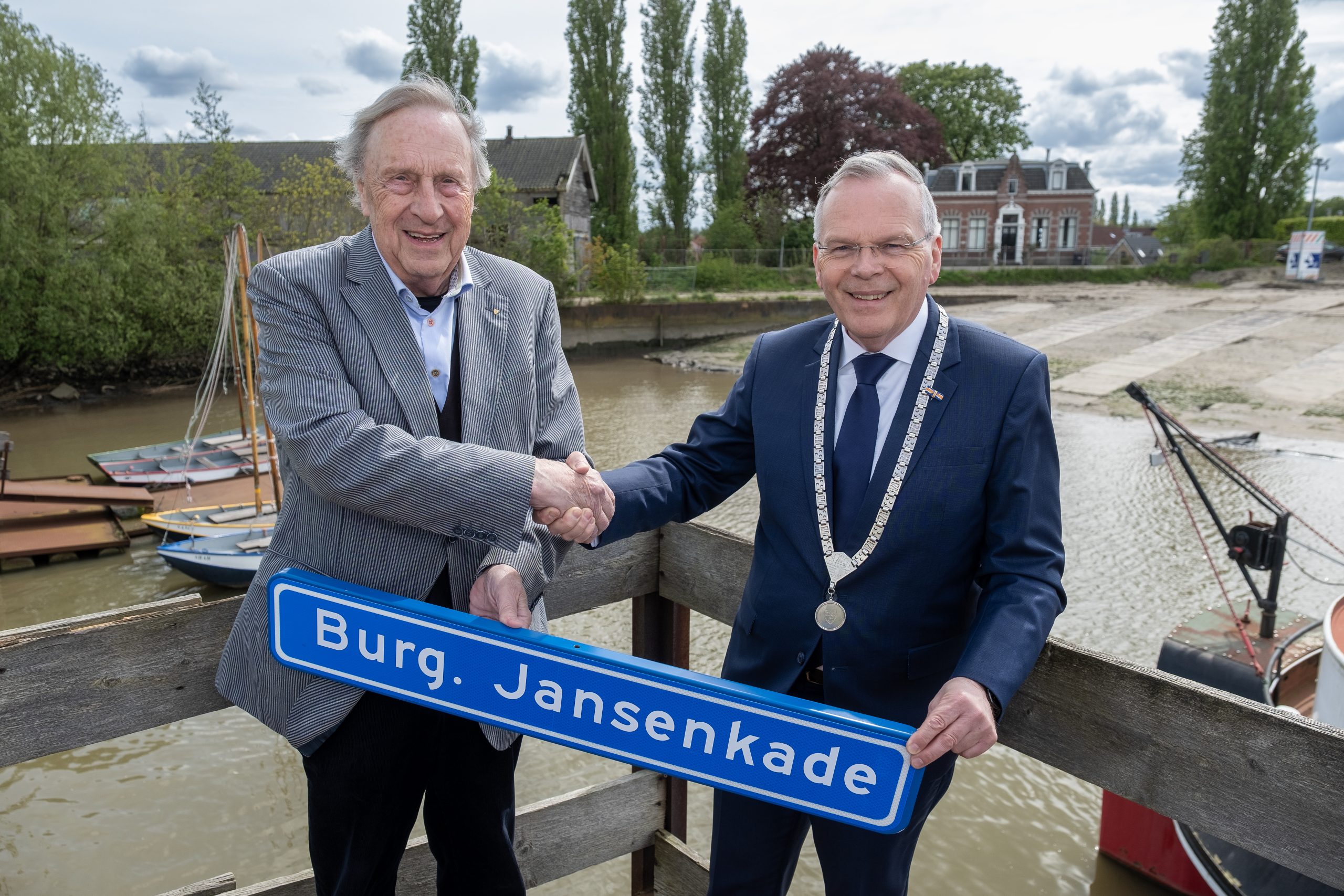 Oud-burgemeester Ries Jansen neemt het straatnaambord met Burgemeester Jansenkade in ontvangst uit handen van burgemeester Jan Luteijn.