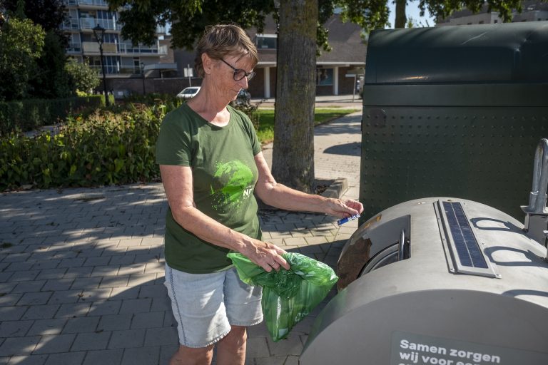 Afbeelding van inwoner die afvalzak in container gooit.