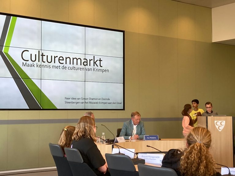 Kindergemeenteraadsleden presenteren culturenmarkt in de raadzaal van het raadhuis.
